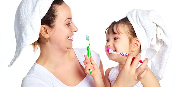 mother and daughter brushing teeth having fun