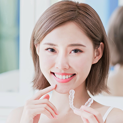 woman holding clear aligner smiling