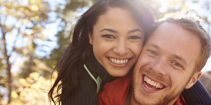 Couple with white teeth smiling in the park