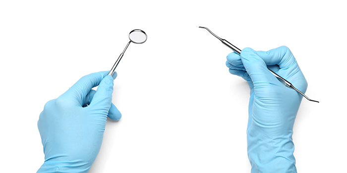 dentist holding small mirror and scaler