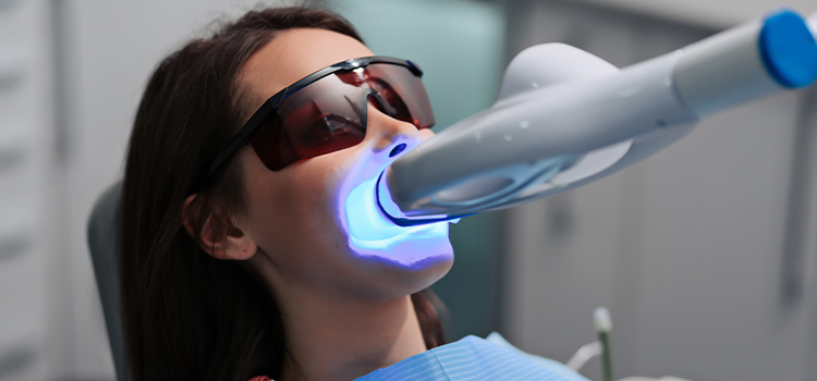 Woman undergoing a Zoom Teeth Whitening Treatment with the UV light on her teeth